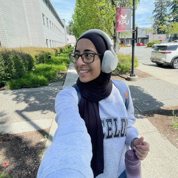 women with glasses and headphones taking a selfie outside 