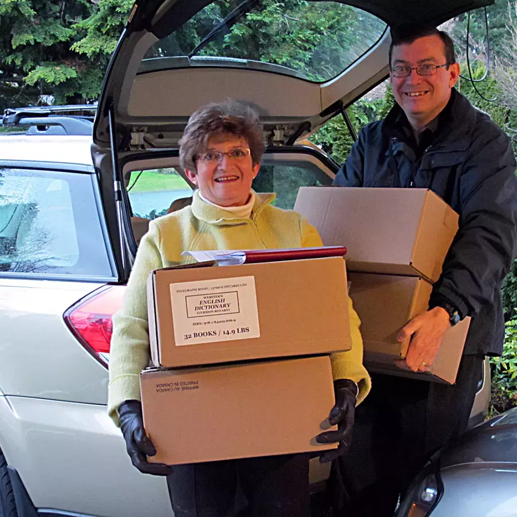 John Shepherd with fellow North Delta Rotary Club member Lornell Ridley carrying boxes of Rotary dictionaries.
