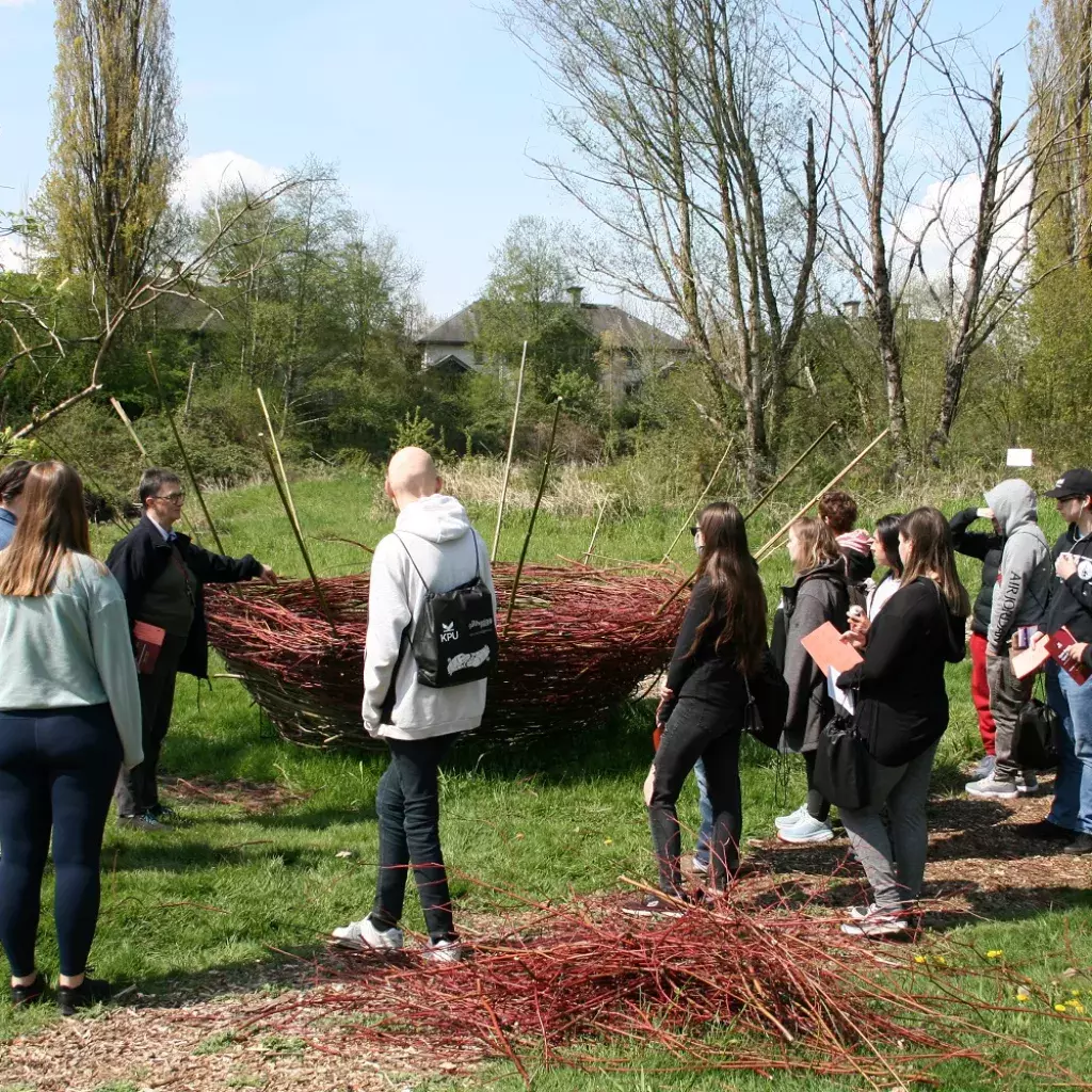 A horticulture instructor shows students a branch weaving project along the Logan Creek flood plain