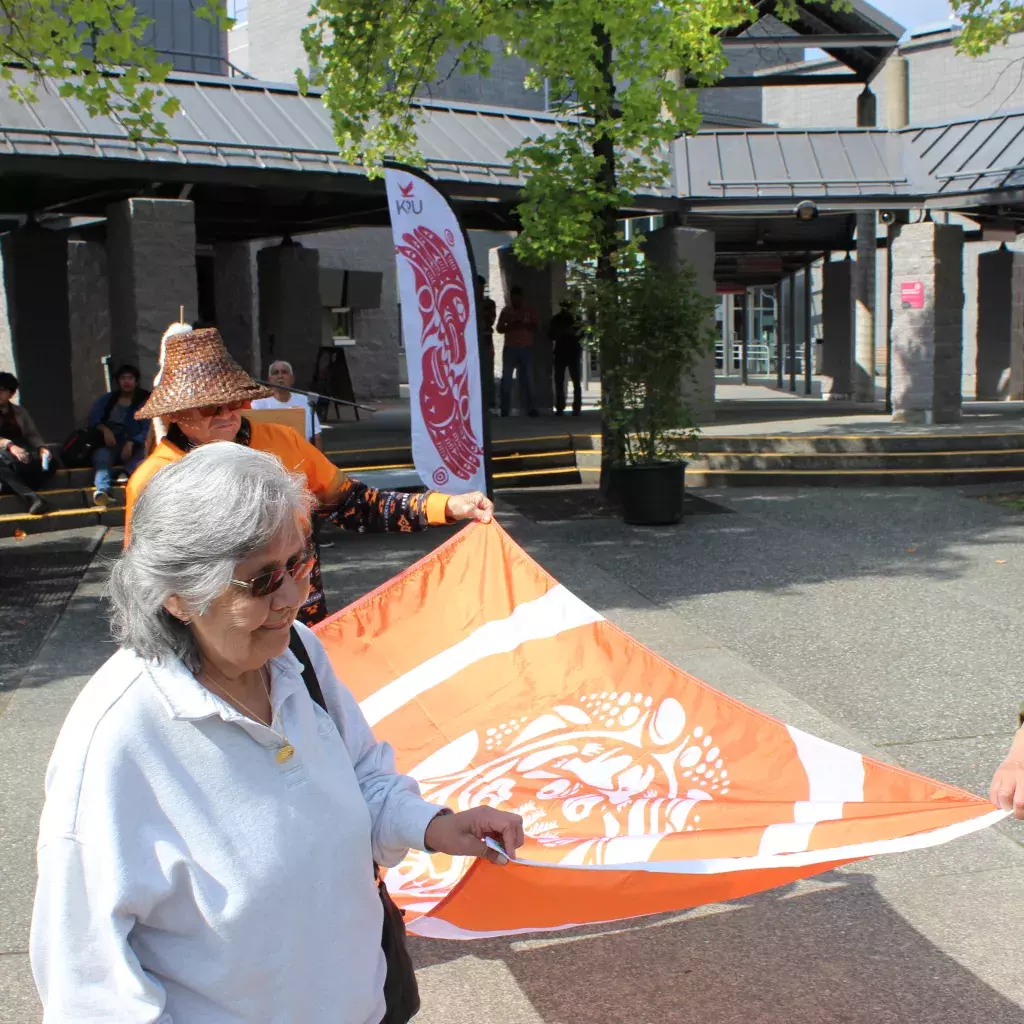 Indigenous Elders carrying KPU's Reconciliation flag to be raised in the Surrey campus courtyard